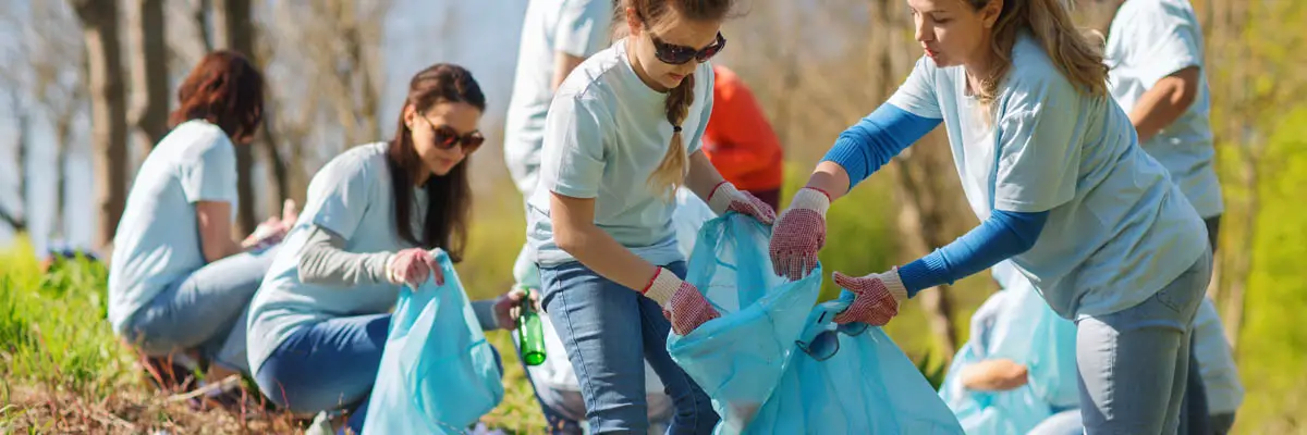 A group of volunteers outside putting trashing into a bag.